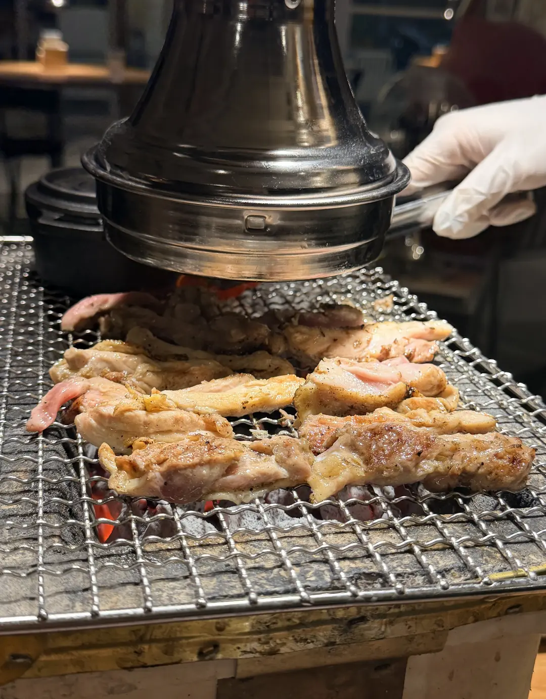 店员戴手套在炭火烤炉上为客人烤鸡肉